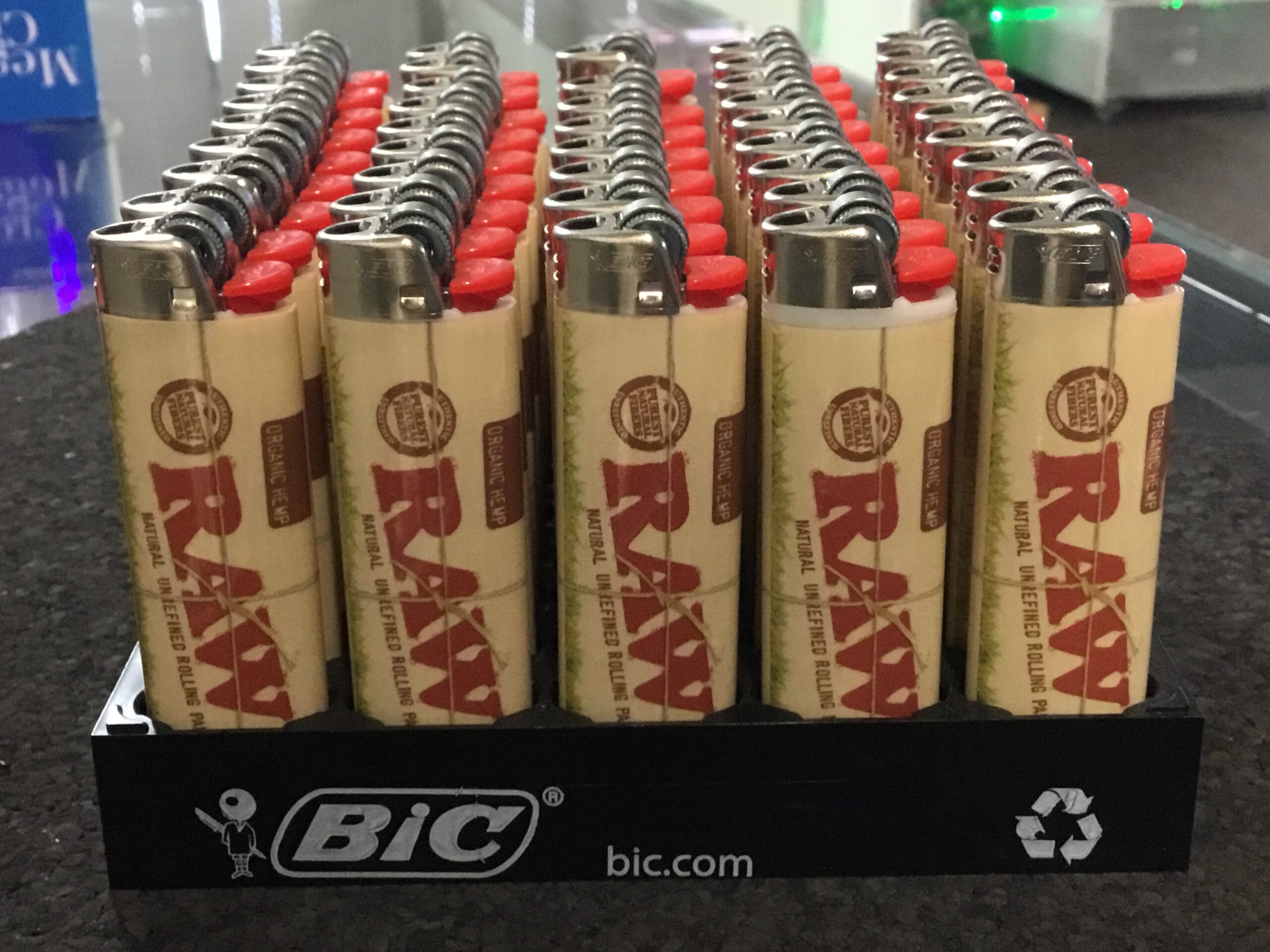 A display tray filled with RAW-branded BIC lighters, arranged in rows, with the BIC logo and recycling symbol on the front—perfect for any Florida mobile smoke shop or Winter Haven event.
